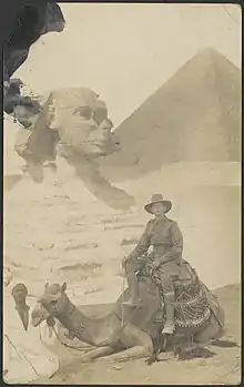 Photographie noir et blanc avec Charles Ulm sur un chameau devant le Sphinx.