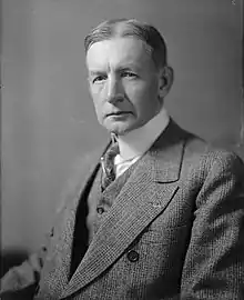 Photo en noir et blanc d'un homme en costume, vue de trois quart.
