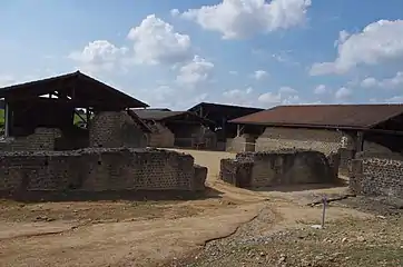 Vue plein ouest depuis le natatio (piscine froide) du coin sud-est. L'alveus (petit bassin) dans le bâtiment à gauche est contigü au frigidarium (salle froide) qui se trouvait à sa droite (vers le fond de la cour). Bâtiment à droite : le palestre / gymnase du côté sud de l'entrée (on retrouve aussi son pendant du côté nord de l'entrée).