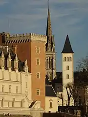 Photographie en couleurs d'un château, d'un clocher et d'un beffroi.
