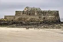 Cavaliers sur une plage, au pied d'un fort.