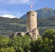 Photo d'une tour ronde devant un paysage de montagne.