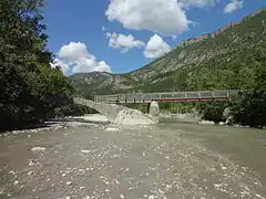 Passerelle piétonne établie sur les piles restantes d'un pont muletier emporté par une crue.