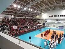 Une équipe de volleyball devant une tribune rempli de spectateurs.