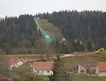 Des maisons blanches au toit rouge avec en arrière-plan un tremplin.