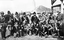 Des soldats en uniforme, posant avec des hommes en armes coiffés de toques de fourrure.