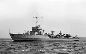 Photographie en noir et blanc d'un navire de guerre en mer, la proue pointant vers la gauche de l'image.