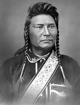 Portrait noir et blanc d'un Amérindien en tenue traditionnelle coiffé de deux tresses.