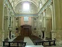 Photographie couleur de la nef baroque d'une église, vue vers la façade.