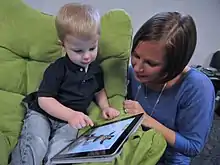 Un enfant avec sa maman devant une tablette.