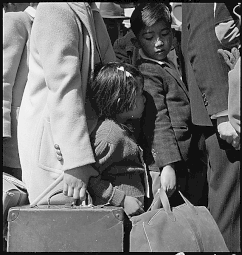 Byron, en Californie. Troisième génération d'enfants américains d'ascendance japonaise en foule attendant l'arrivée du prochain bus qui les emmènera de chez eux au centre de regroupement (Assembly center). 2 mai 1942.