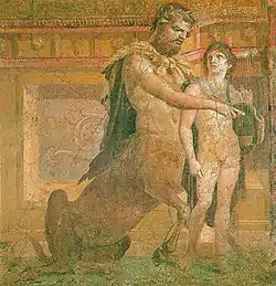 Un centaure, assis sur son postérieur, entoure de ses bras un jeune garçon nu, et joue sur la lyre que ce dernier tient.