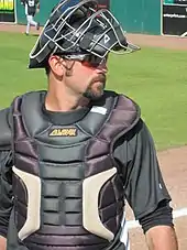 Un joueur de baseball en tenue avec un casque et un gilet de protection.