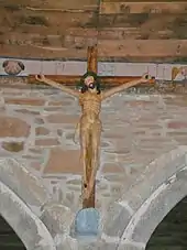 Photo d'un grand Christ en croix sur un mur entre deux arcades