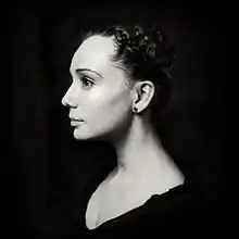 Buste en noir et blanc contrasté d'une jeune femme pâle de profil, cheveux tirés, traits fins, grand front, grands yeux noirs
