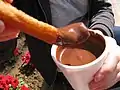 Chocolat fondu dans un gobelet pour tremper des churros.