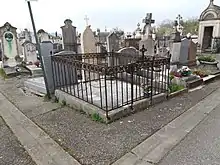 Photo d'une tombe au milieu d'un cimetière.