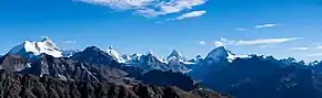 Photographie de plusieurs montagnes au fond d'une vallée. Les plus hautes sont enneigées. Les deux premières à partir de la gauche ont un sommet pointu tandis que les autres sont arrondies.