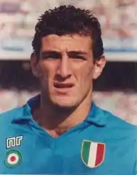 Photographie d'un joueur de football aux cheveux courts, bruns, avec un maillot bleu ciel, vu en gros plan.