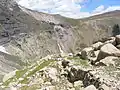 Chemin des mines dans le granite du gros épaulement du cirque, avec au deuxième plan la falaise nord et au loin le port de Barroude