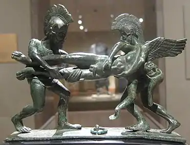Statue en bronze de deux soldats avec casques à crête et armures, en train de se disputer un corps.