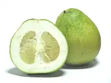 Un agrume vert jaunâtre en forme de poire à peau épaisse et pulpe vert jaune