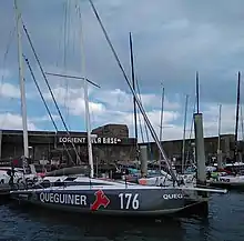 Vue latérale d'un voilier gris et blanc amarré au ponton.