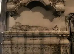 Photographie couleur montrant un gisant de femme sur un tombeau de marbre surmonté d'un dais également de marbre.