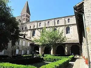 Cloître roman doiné par une église romane de grandes dimensions.