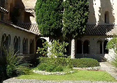 Cloître de Gellone, la galerie ouest sur la gauche et la galerie nord au fond, percées d'arcades géminées.