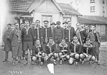 Photographie en noir et blanc d'une équipe sportive avec des joueurs et entraîneurs debout et d'autres accroupis.