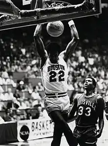 Clyde Drexler dunkant à deux mains, sous les yeux d'un adversaire.