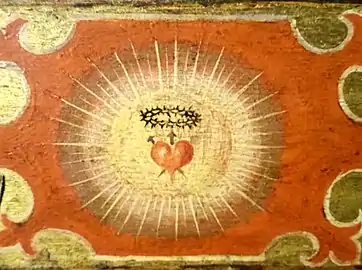 Détail d'un panneau représentant le cœur rayonnant de Jésus-Christ, prémices de la dévotion au Sacré-Cœur.