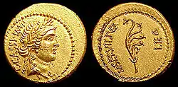 Pièce en or. À gauche, Caius Cassius, imperator, tête laurée de la Liberté. À Droite, Marcus Servilius, légat, avec un aplustre, ornement de la poupe d’un navire en forme d’éventail; avec chaque branche se terminant par une fleur.