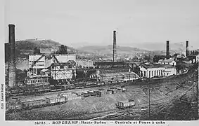 Un ensemble industriel surmonté de deux trémies en béton et de quatre hautes cheminées.