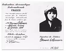 Document papier où figure sur la partie gauche la certification que « Mme Bessie Coleman, né[e] à Atlanta, Texas, le 20 janvier 1896, ayant rempli toutes les conditions imposées par la F.A.I a été breveté Pilote-Aviateur à la date du 15 juin 1921. » Sur la partie droite figure la photographie d'une femme en gros plan portant un casque d'aviateur, en dessous de laquelle apparaît la signature de Bessie Coleman ainsi que le numéro du brevet : 13810.