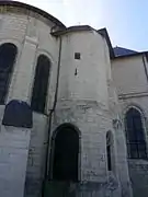 Photographie en couleurs d'une pièce munie d'une meurtrière surmontant l'absidiole d'une église fortifiée.