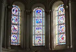 Photographie en couleurs de trois grandes verrières dans le chœur d'une église.