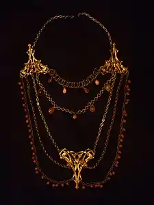 Long collier dit sautoir. La mode est au bijou fantaisie (laiton, verre, corail…).