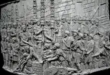 bas-relief rectangulaire convexe, montrant un homme sur un autre ; un autre s'agenouille devant lui ; autour d'eux, de nombreux soldats et prisonniers.