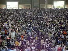 De nombreuses personnes sont réuniens dans un très grand hall.