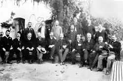 Photographie noir et blanc : un groupe d'hommes posant en demi-cercle.