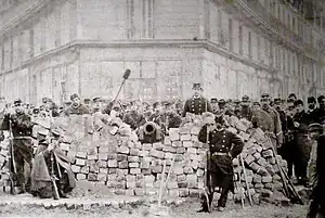 Mur de pavés avec des canons et des soldats qui posent autour.
