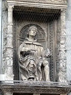statuette d'homme assis tenant un livre à la main, sous un dais de quatre colonnes décorées.