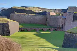 photographie montrant au premier plan la Porte de Brisach, les fortifications murs d'enceinte de la partie nord, à l'arrière-plan, la Tour des Bourgeois et la citadelle