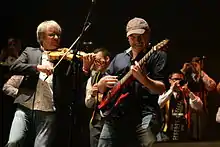 Violoniste et guitariste de Red Cardell devant les sonneurs de bombardes du bagad.