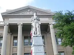 Statue d'un soldat avec chapeau tenant son fusil debout devant lui.