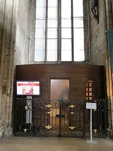 Photo du confessionnal à la paroi bombée avec une porte vitrée en partie centrale