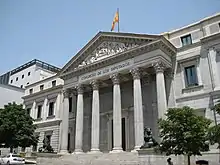 Photographie d'un bâtiment public, avec six colonnes doriques en façade et le drapeau espagnol sur le toit.