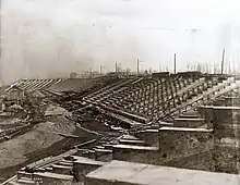 Vue d'un stade en construction, de nombreuses planches jonchent le sol.